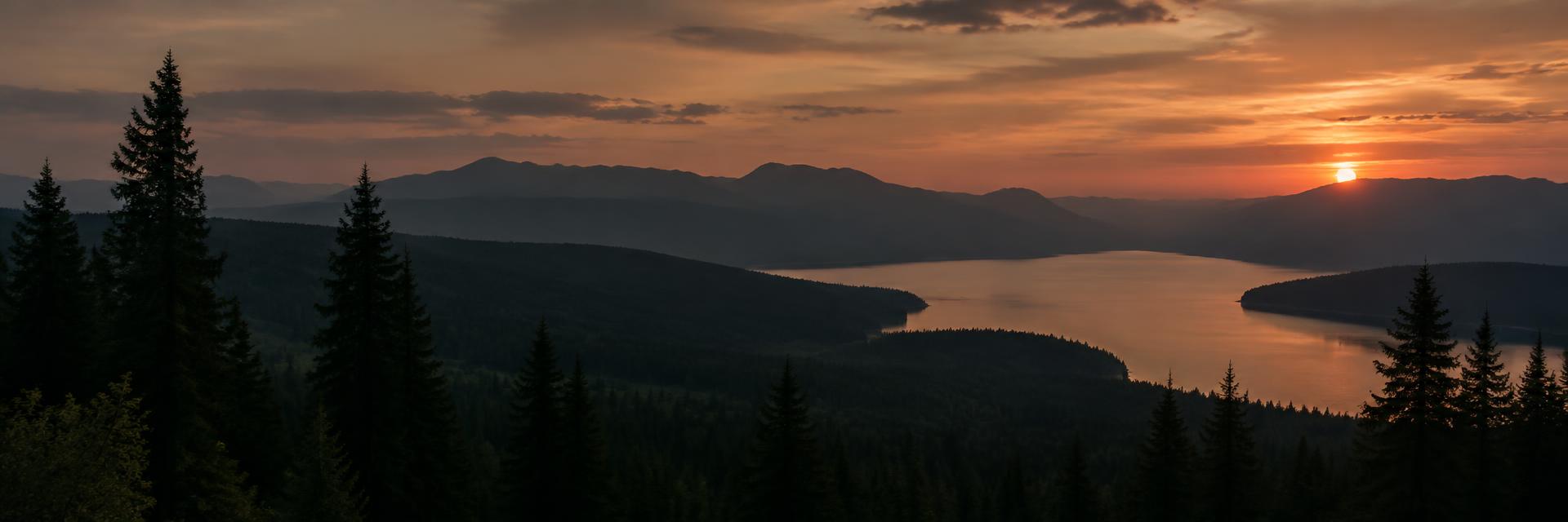 Forested mountains and lake at sunset